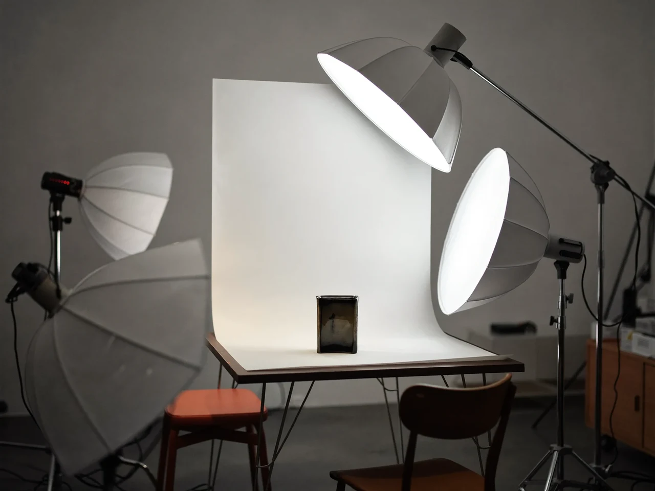 Světlý ateliér se stolní sestavou, softboxy a keramickým předmětem na papírovém pozadí